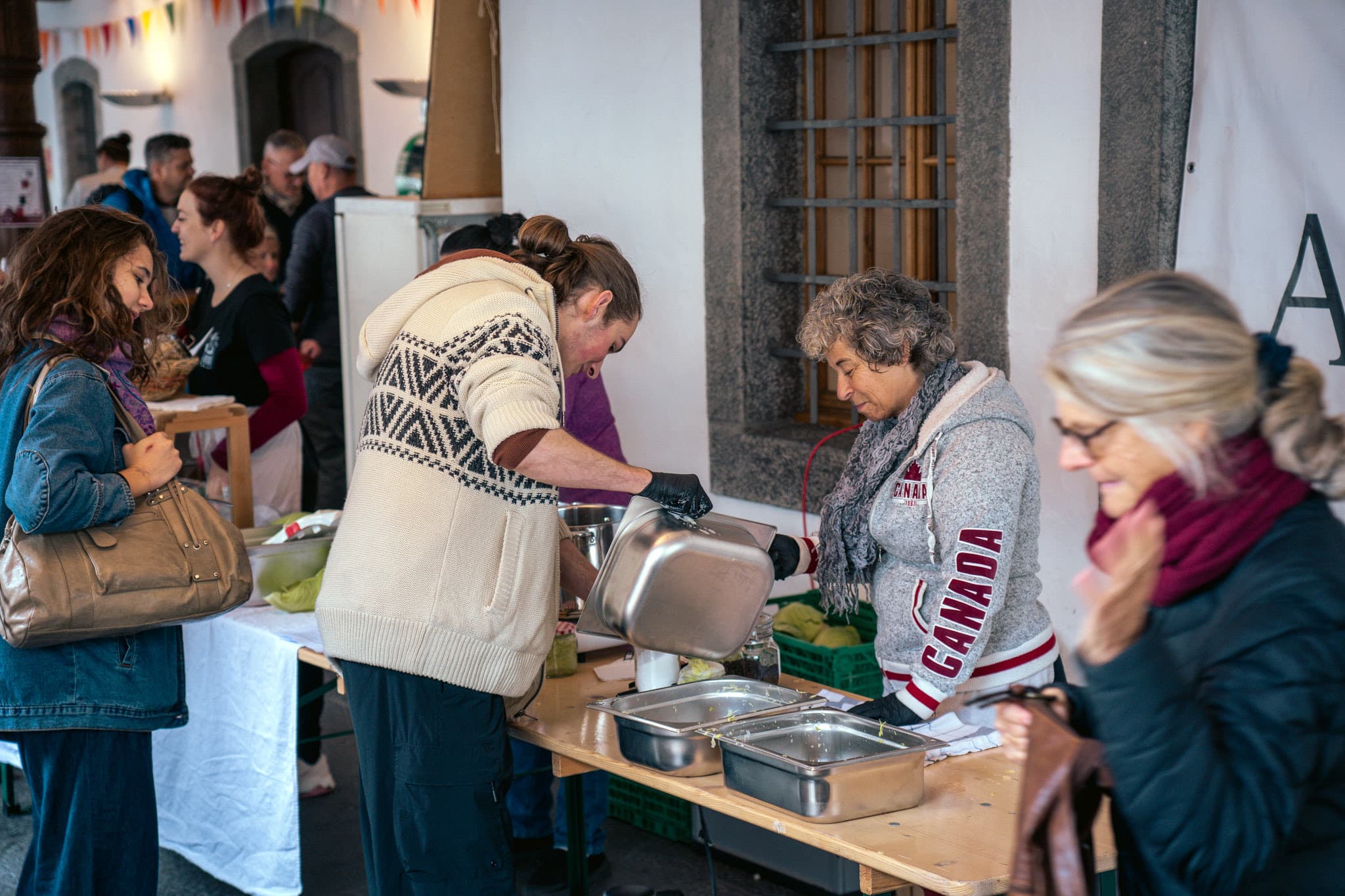 Am Foodsave Bankett in Thun stehen mehrere Menschen an einem Tisch und hantieren mit Catering-Schalen mit Lebensmitteln.