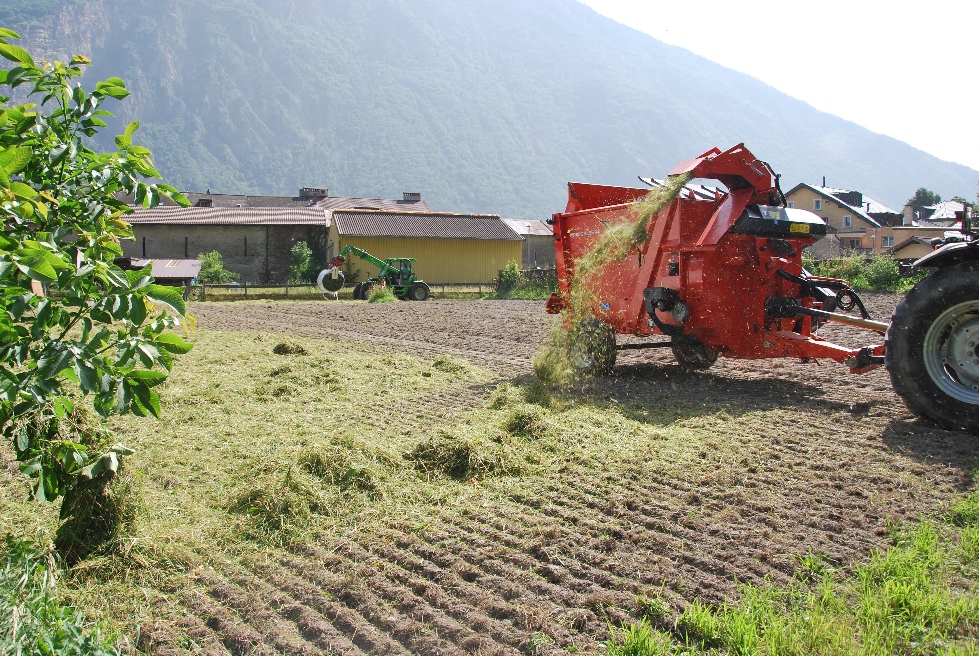 Eine Landwirtschaftsmaschine bläst das Schnittgut auf den Acker.